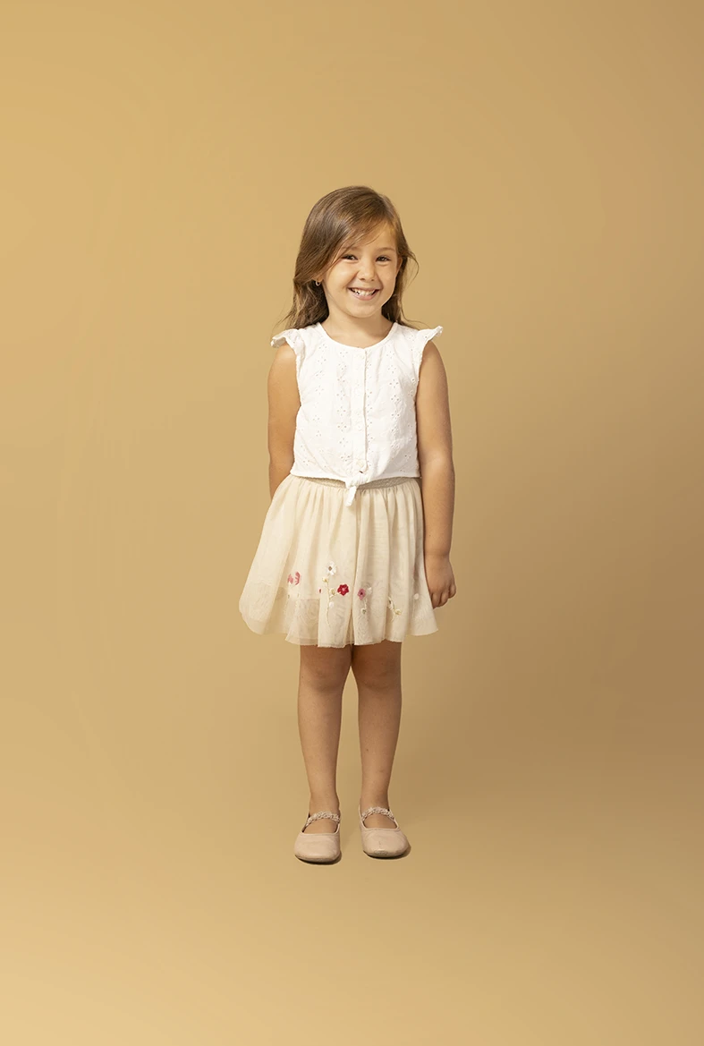 Niña posando con falda clara y camiseta blanca. Fotógrafo de niños para agencia en Mallorca.