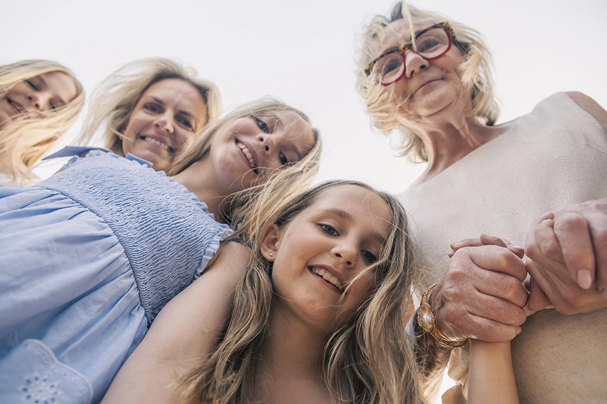 Cuatro generaciones de mujeres sonrientes vistas desde abajo durante una sesión con fotógrafo familiar en Mallorca. Foto de Inma del Valle.