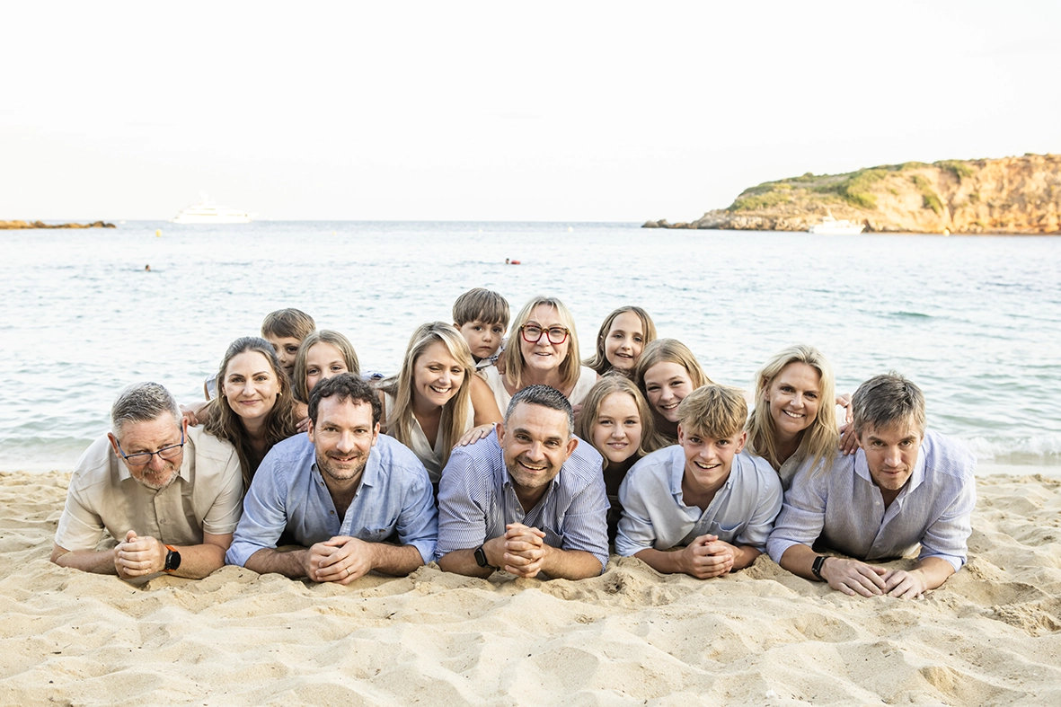 Retrato de familia irlandesa tumbada en la arena frente al mar, tomado por fotógrafo familiar en Mallorca, Inma del Valle.