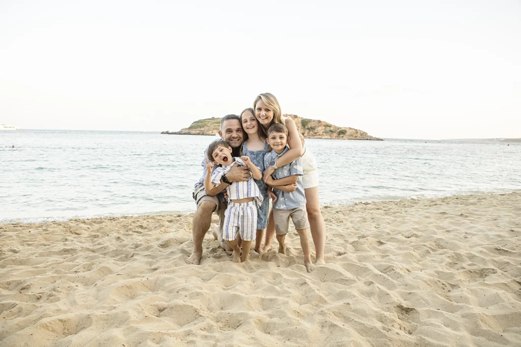 Niños abrazándose en la playa durante una sesión con fotógrafo familiar en Mallorca, realizada por Inma del Valle.
