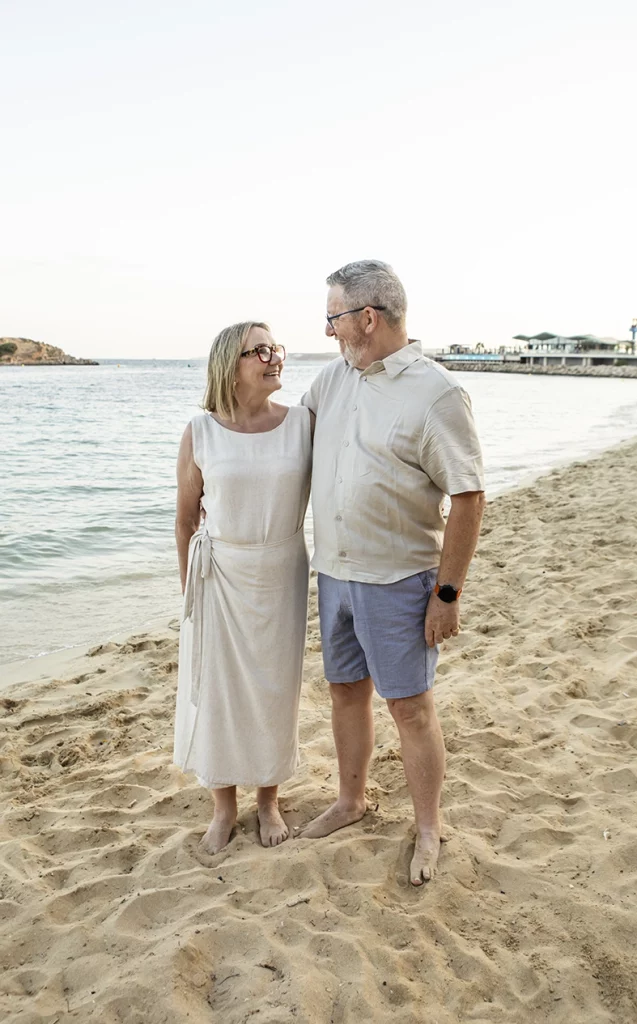 Pareja mayor mirándose con cariño en la playa durante una sesión con fotógrafo familiar en Mallorca, Inma del Valle.