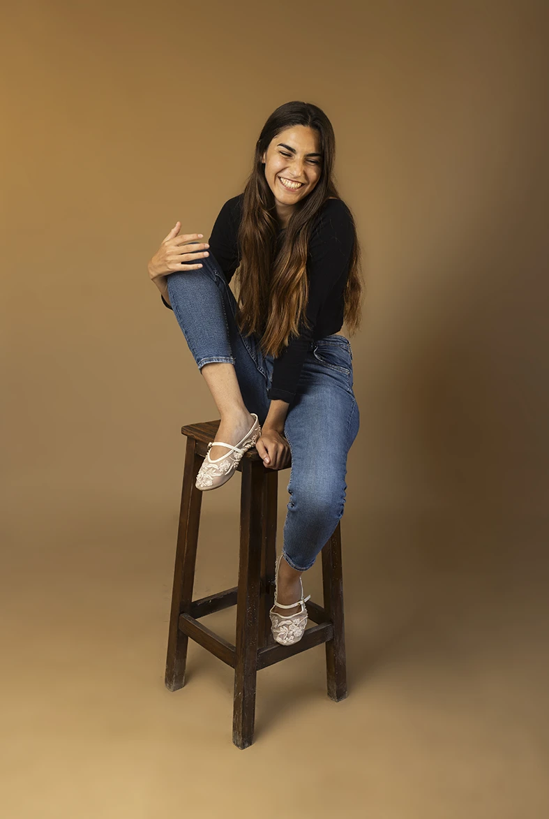 Young model posing on a stool with neutral background, professional photo session in Mallorca. How you can become a model in Mallorca. Photo by Inma del Valle.