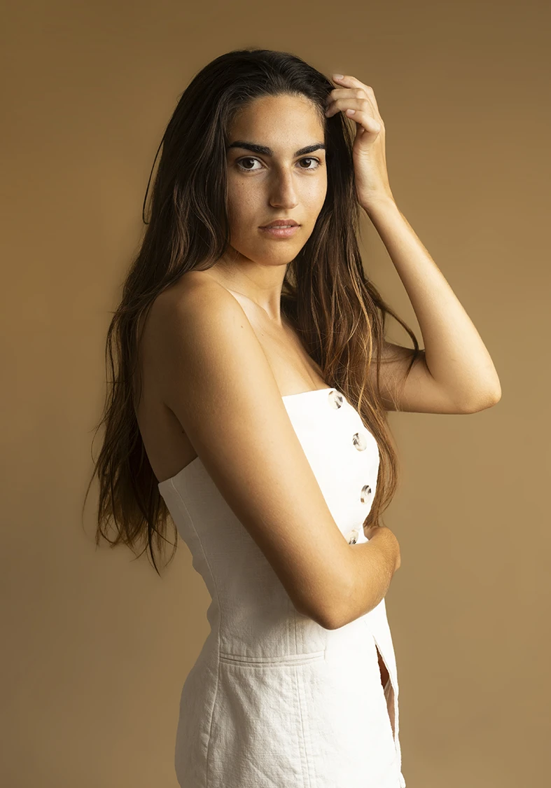 Medium shot of a model posing with hand in hair, serious expression, neutral background. How you can become a model in Mallorca. Photo by Inma del Valle.
