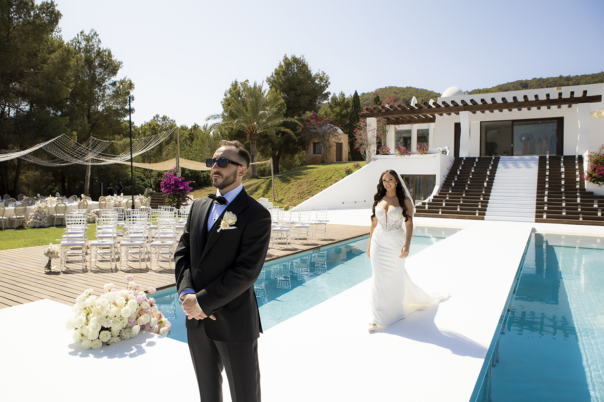 Kyle standing with his back turned as Rachel walks up behind him for the first look at their luxury wedding in Ibiza, photographed by Inma del Valle.
