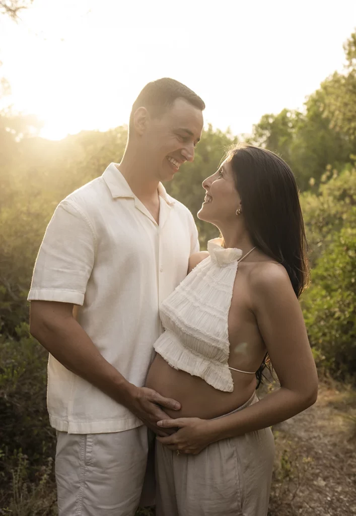 Pregnant couple looking at each other tenderly during a pregnancy photo shoot in Mallorca at sunset.
