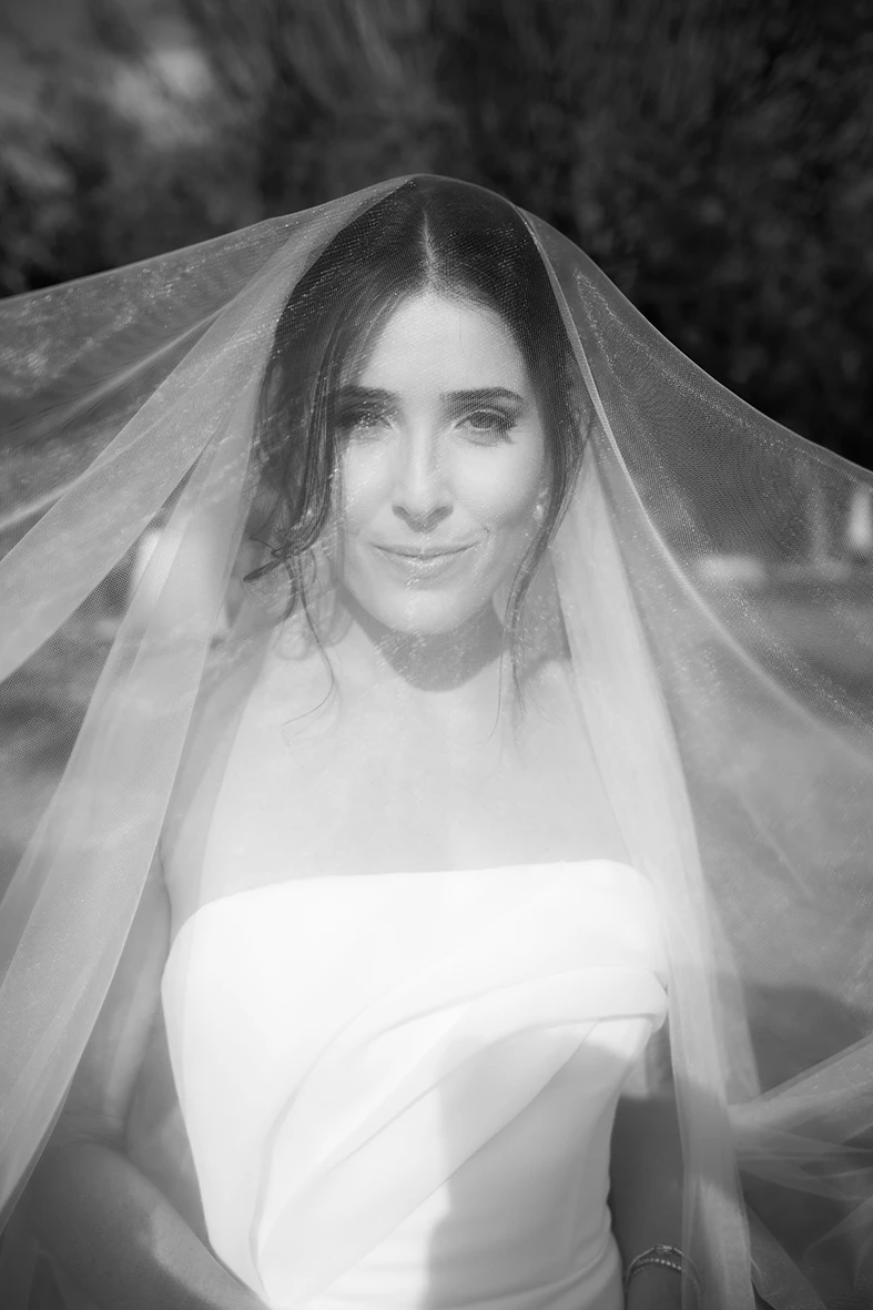 Bride in black and white portrait with wedding veil covering her face in Mallorca.
