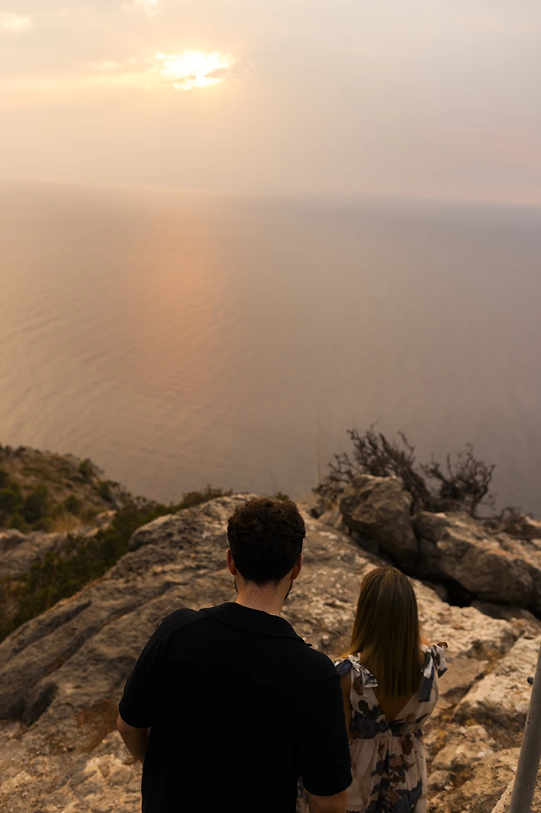 Couple sitting and gazing at the sea after their proposal in Mallorca. Photo by Inma del Valle, photographer of marriage proposals in Mallorca.
