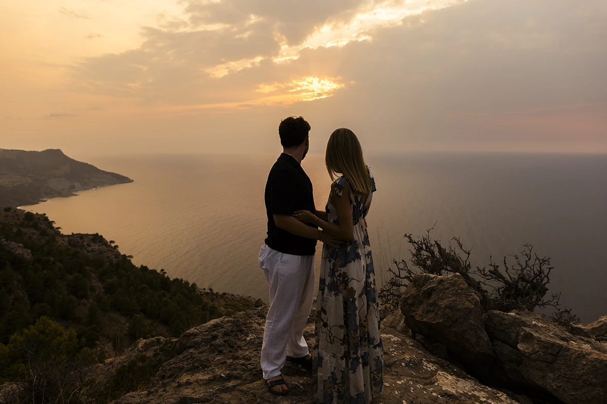 Couple holding hands watching the sunset in Mallorca. Photo by Inma del Valle, photographer of marriage proposals in Mallorca.