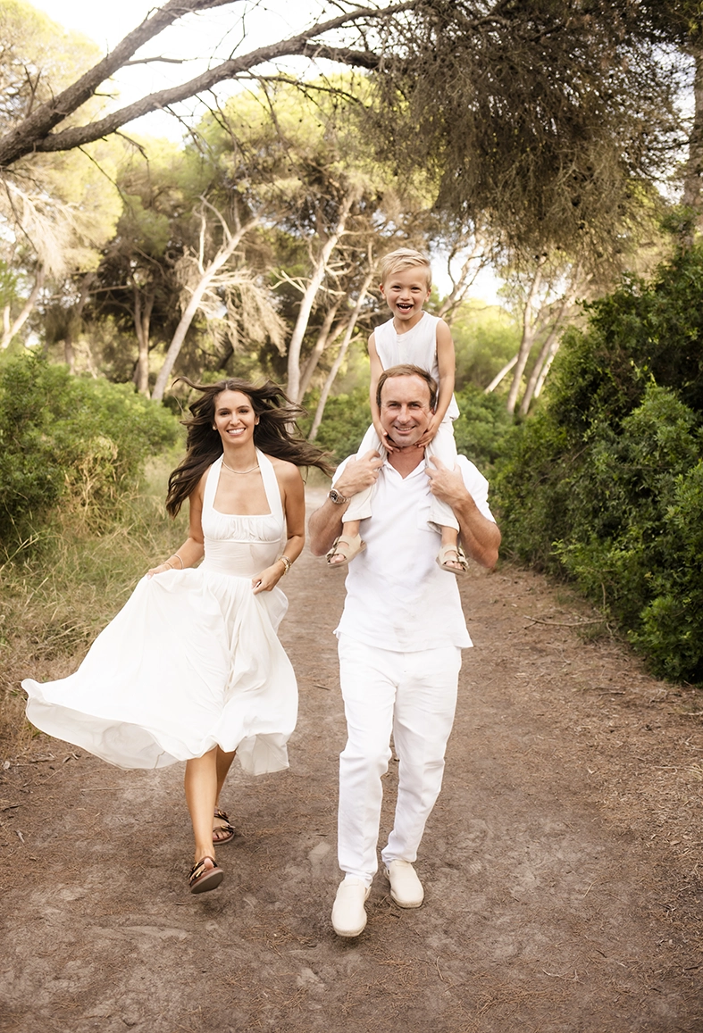 Sesión de fotos a familia en Mallorca realizada por Inma del Valle, familia corriendo por un camino del bosque con sonrisas y movimiento.