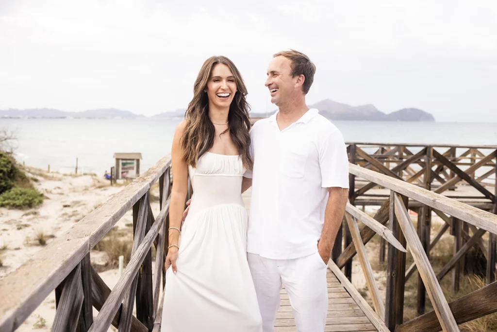 Sesión de fotos a familia en Mallorca realizada por Inma del Valle, pareja sonriendo juntos sobre una pasarela frente al mar.