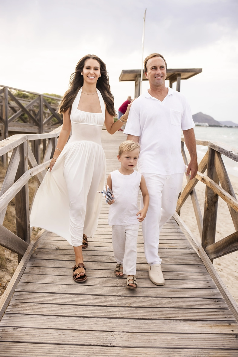 Sesión de fotos a familia en Mallorca realizada por Inma del Valle, familia caminando junta por la pasarela de madera junto al mar.