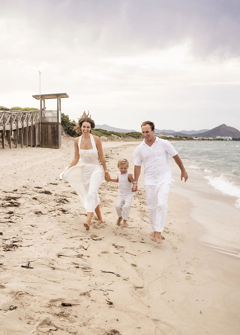 Sesión de fotos a familia en Mallorca realizada por Inma del Valle, familia caminando descalza por la orilla de la playa.