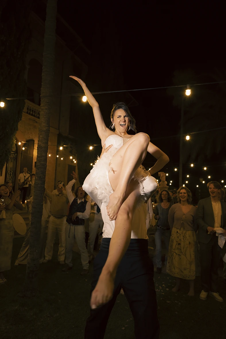 Novia levantada en el aire durante la fiesta con su vestido de novia para la fiesta. Fotografía de Inma del Valle.