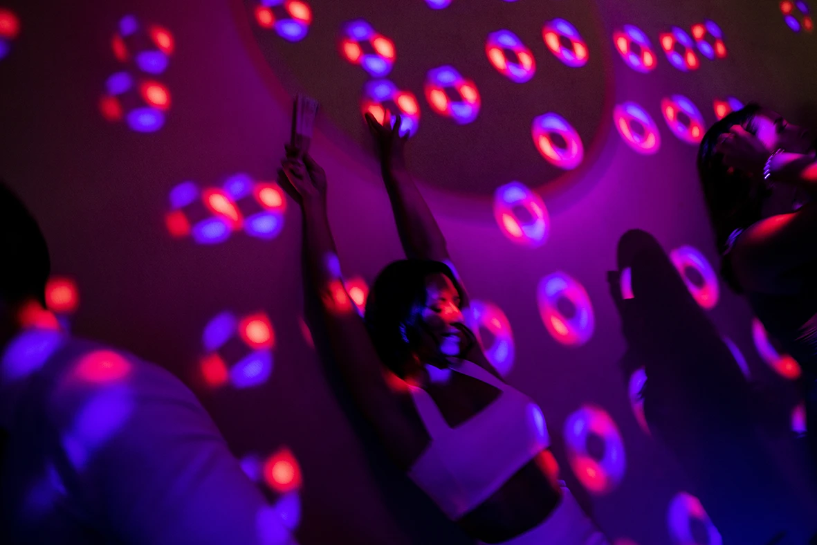 Novia bailando bajo luces de colores con su vestido de novia para la fiesta. Fotografía de Inma del Valle.