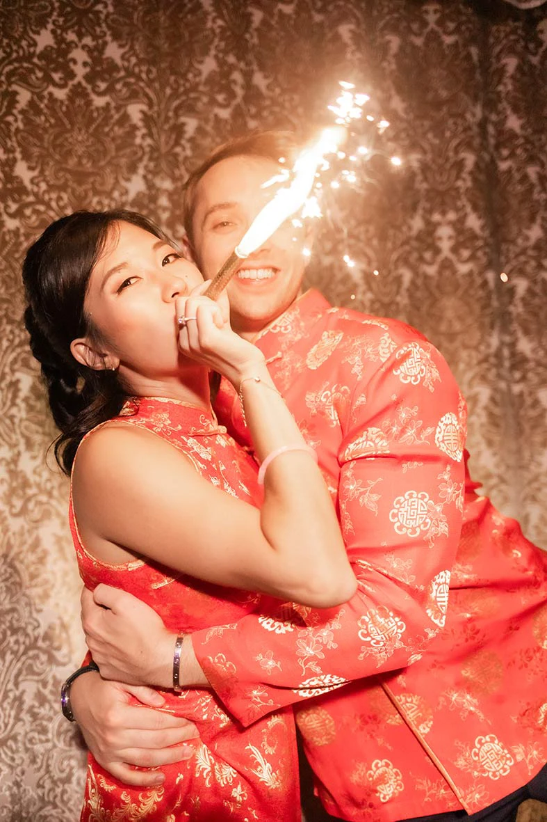 Novia abrazada a su pareja celebrando con bengalas, vestida con un vestido de novia para la fiesta de estilo tradicional. Fotografía de Inma del Valle.