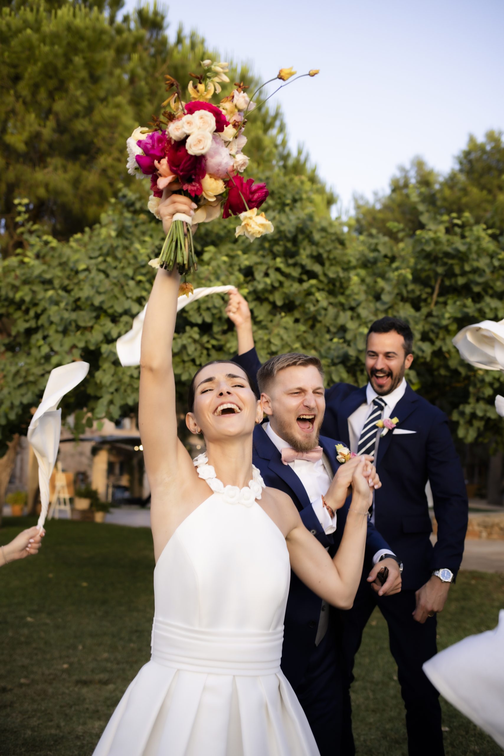 Novia celebrando con el ramo en alto rodeada de invitados, parte de los estilos de boda 2026 en Mallorca.