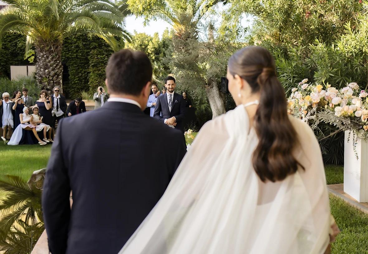 La novia entra al altar del brazo de su padre vista desde atrás – Wedding photographer in Mallorca – Inma del Valle -.