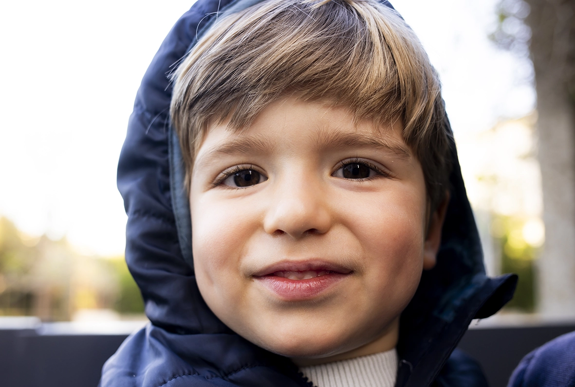 Retrato de un niño sonriente con sudadera, capturado por un fotógrafo para familias en Mallorca.