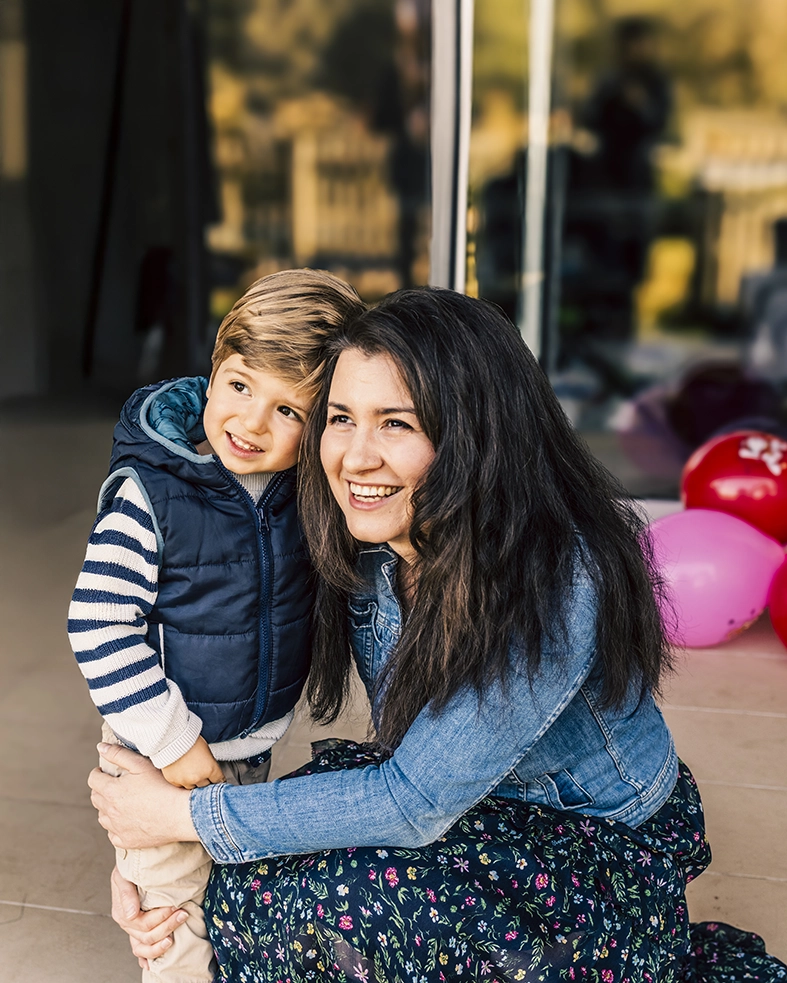 Madre e hijo abrazados con globos de fondo, capturados por un fotógrafo para familias en Mallorca.