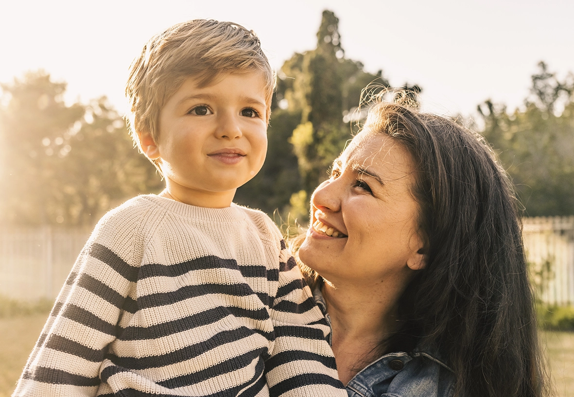 Madre mirando con ternura a su hijo al aire libre, capturada por un fotógrafo para familias en Mallorca.