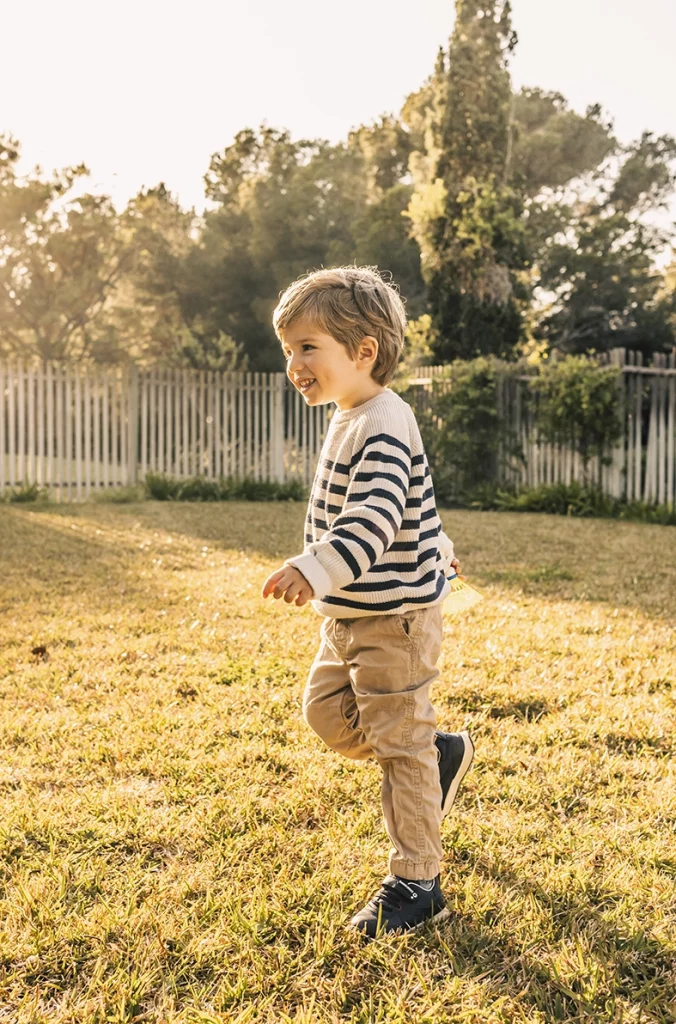 Niño corriendo al aire libre al atardecer, capturado por un fotógrafo para familias en Mallorca.