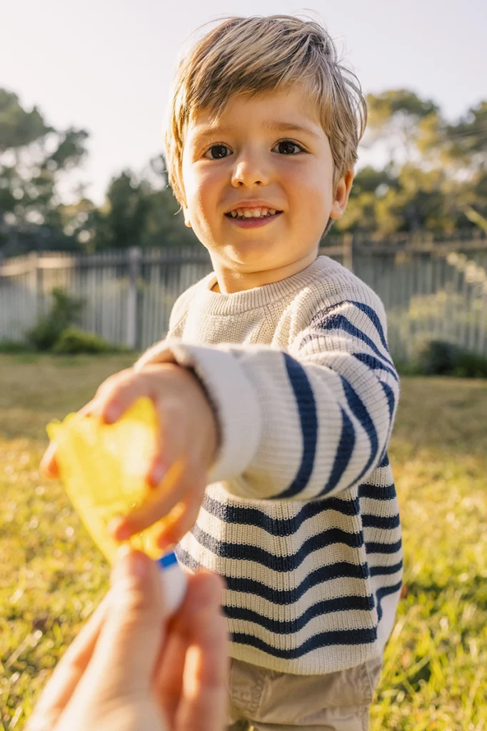 Niño sonriente entregando un juguete amarillo al aire libre, capturado por un fotógrafo para familias en Mallorca.