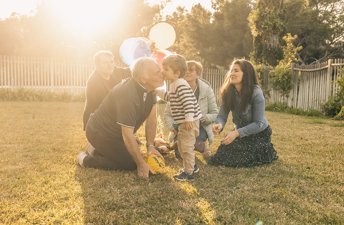 Familia jugando juntos en el césped al atardecer, capturada por un fotógrafo para familias en Mallorca.