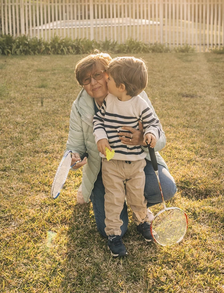 Abuela abrazando y besando a su nieto al aire libre al atardecer, capturada por un fotógrafo para familias en Mallorca.