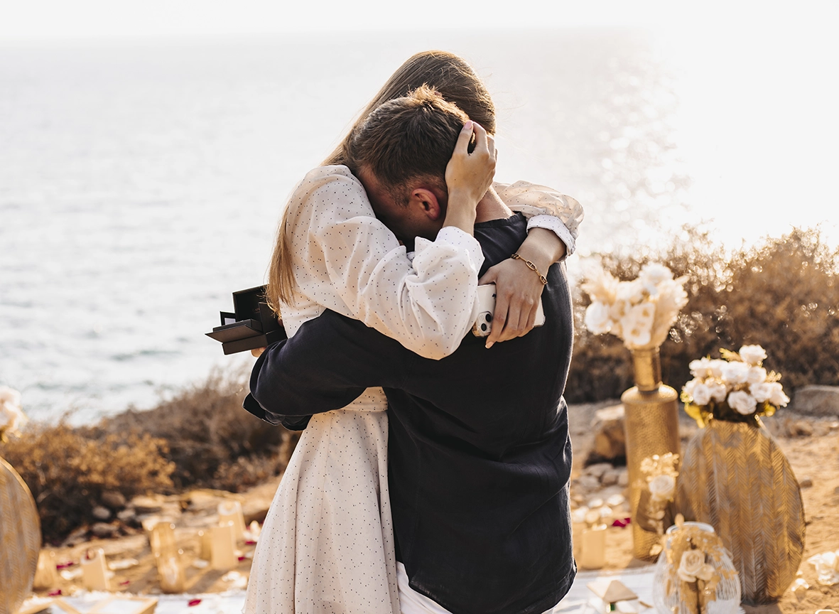 Couple embracing emotionally after the proposal by the sea, captured by a photographer for proposals in Mallorca.