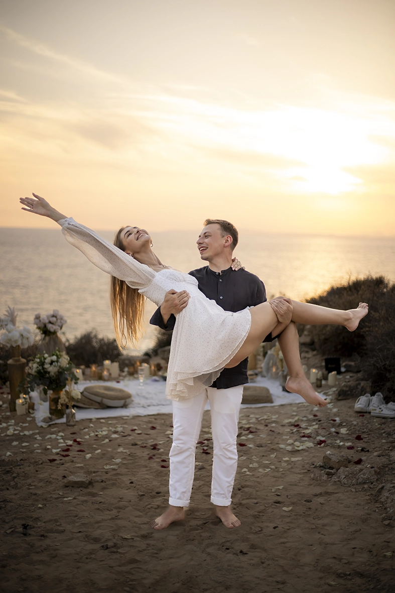 Groom lifting his partner in his arms by the sea during their proposal in Mallorca, captured by a photographer for proposals in Mallorca.