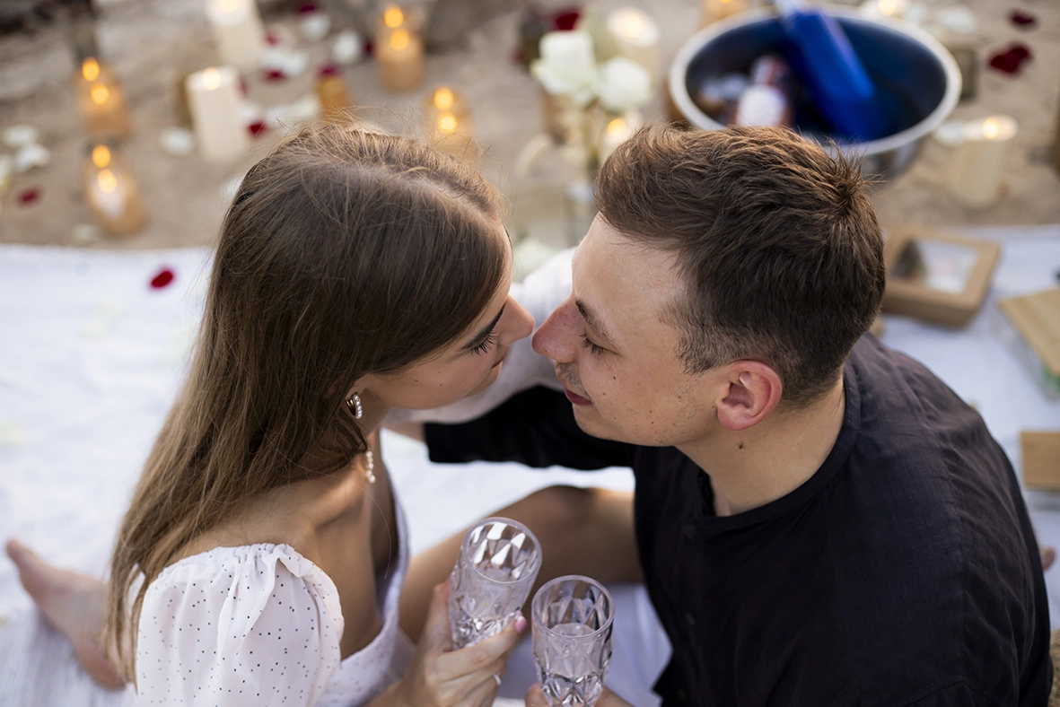 Couple toasting and about to kiss during their proposal in Mallorca, surrounded by candles and romantic decoration. Captured by a photographer for proposals in Mallorca.