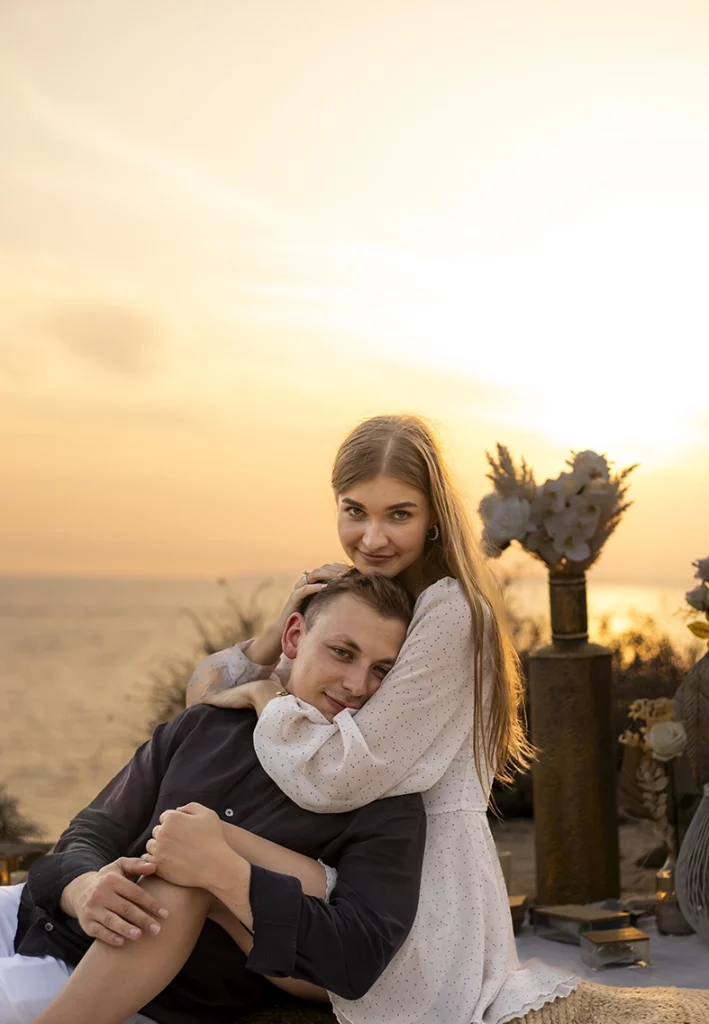Pareja abrazada junto al mar en Mallorca durante su pedida de mano al atardecer, fotografiada por un fotógrafo para pedida de mano en Mallorca.