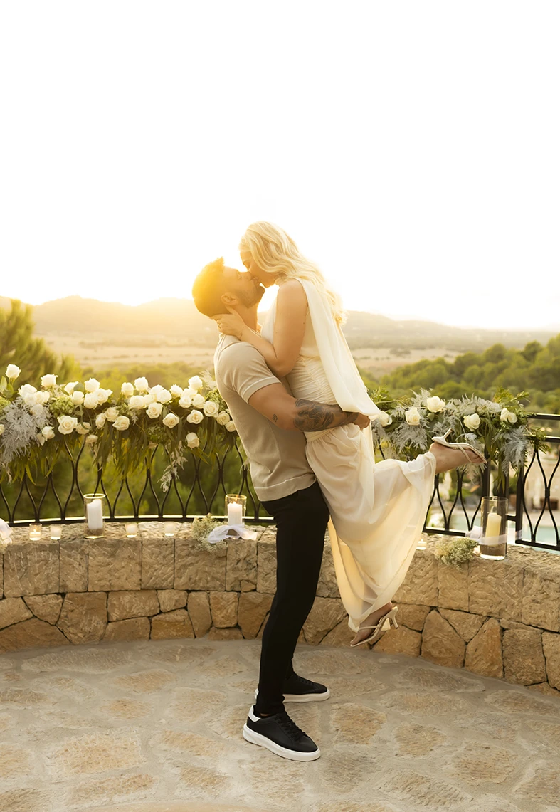 Groom-to-be lifting his fiancée during a romantic proposal in Mallorca.