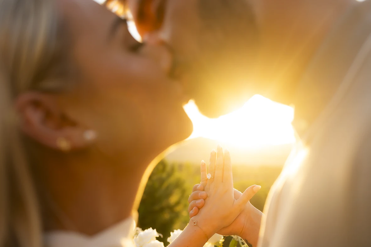 Couple kissing with engagement ring in focus at sunset in Mallorca.