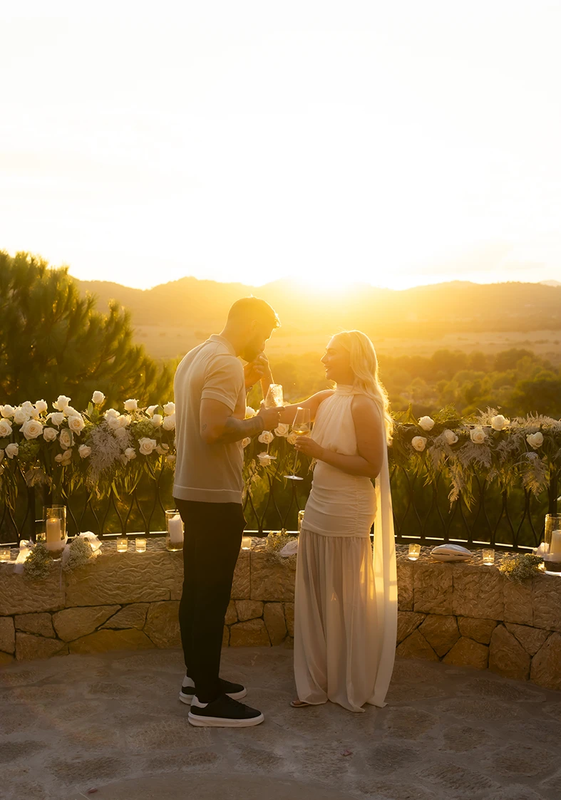 Couple toasting with champagne during their proposal in Mallorca.