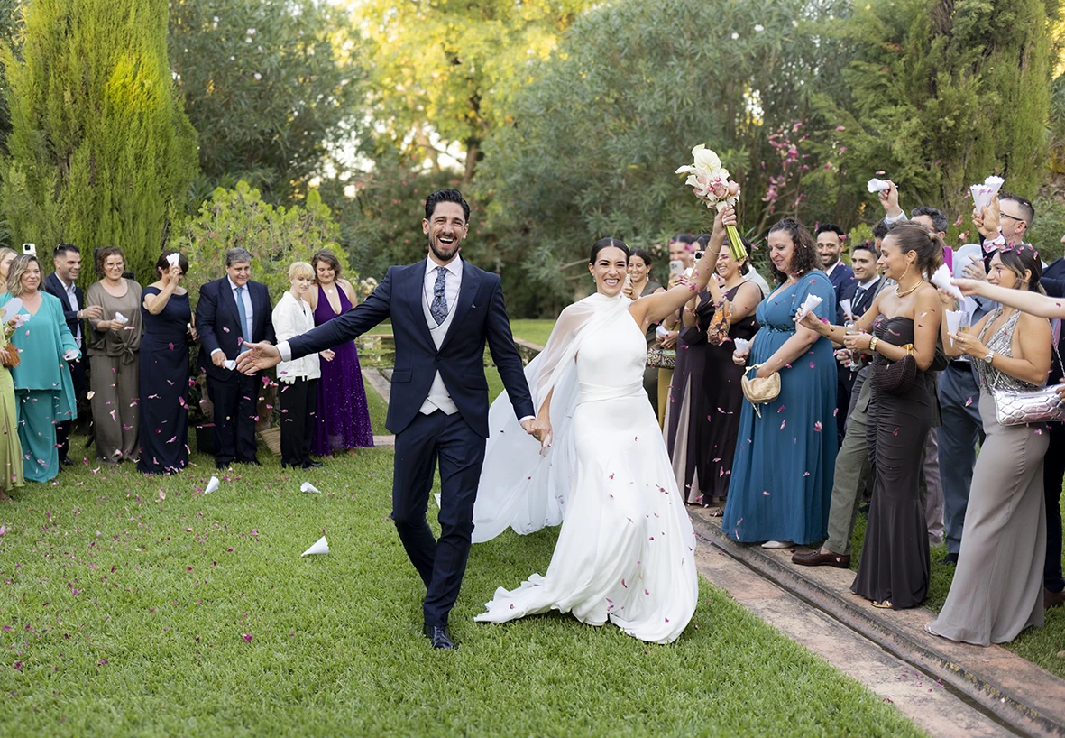 Bride and groom walking out among applause and flower petals – Wedding photographer in Mallorca – Inma del Valle –