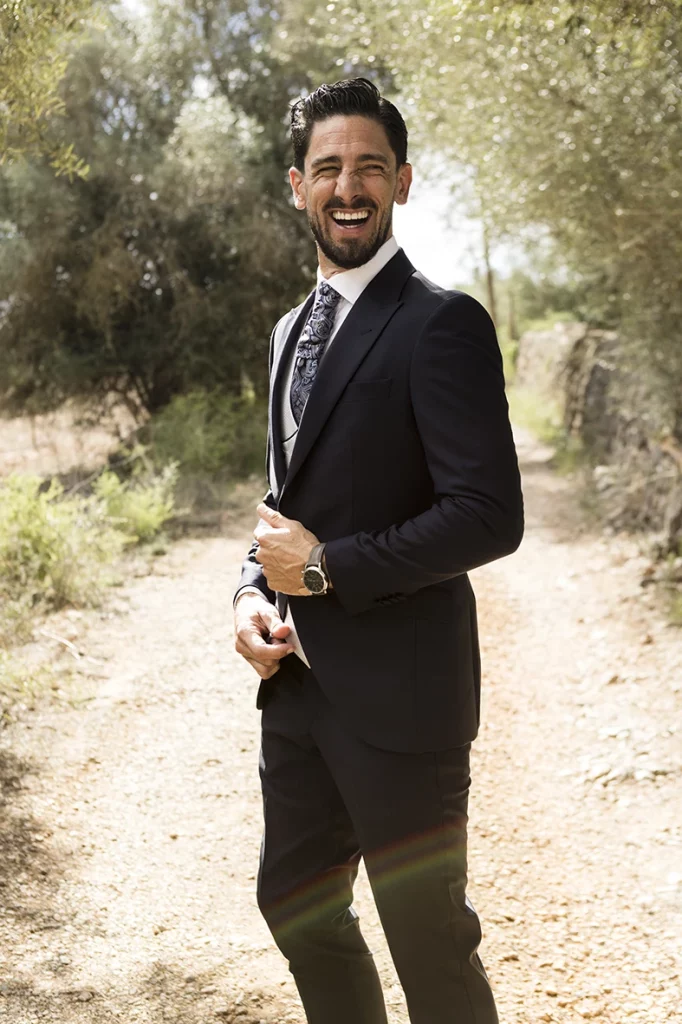 Smiling groom adjusting his watch on a rural path – Wedding photographer in Mallorca – Inma del Valle –