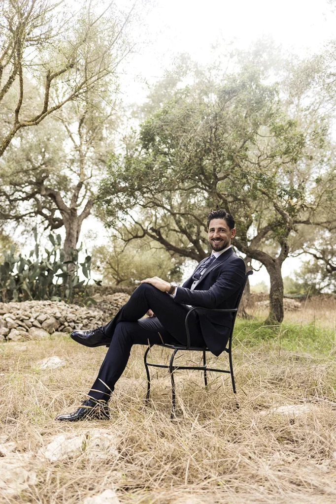 Elegant groom sitting outdoors among olive trees – Wedding photographer in Mallorca – Inma del Valle –