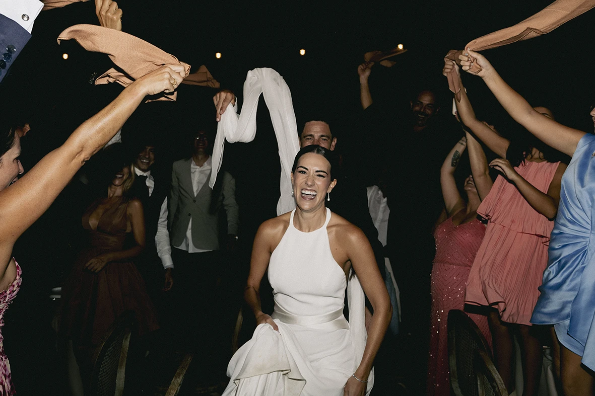 Bride smiling and dancing surrounded by guests during her wedding celebration in Mallorca.
