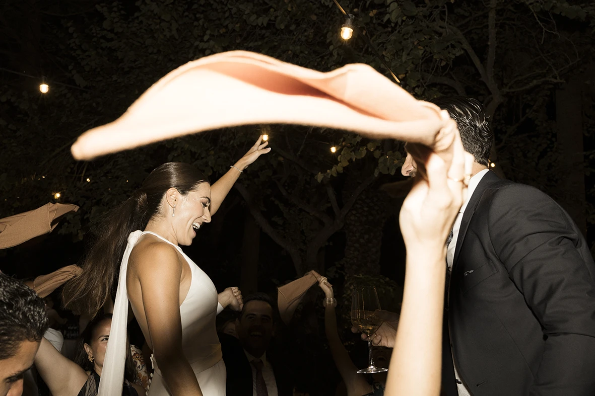Bride dancing while guests wave napkins during a festive wedding party in Mallorca.