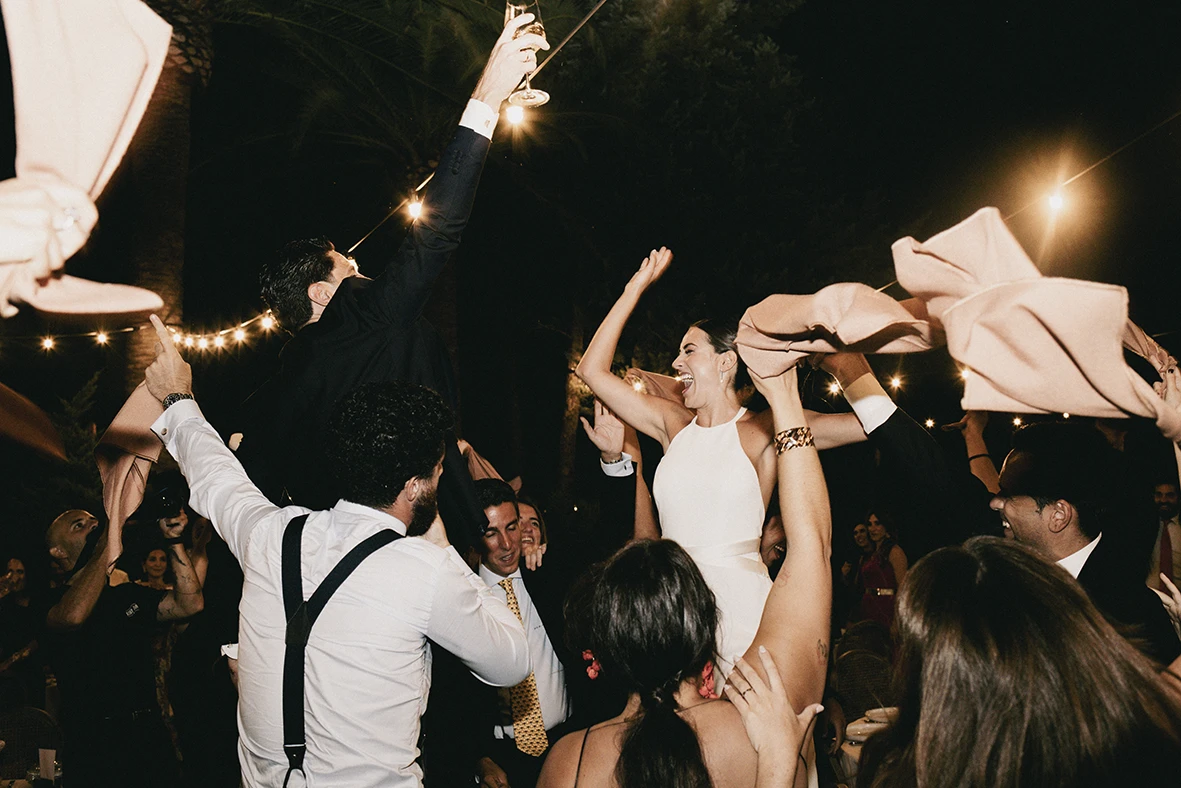 Bride dancing with guests raising their arms during a lively wedding celebration in Mallorca.