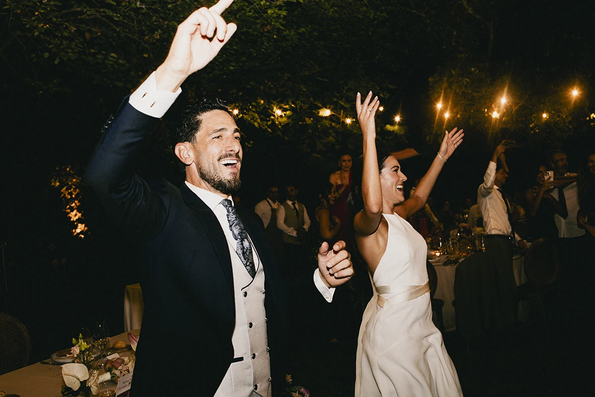 Bride and groom dancing with raised arms during their wedding party in Mallorca.
