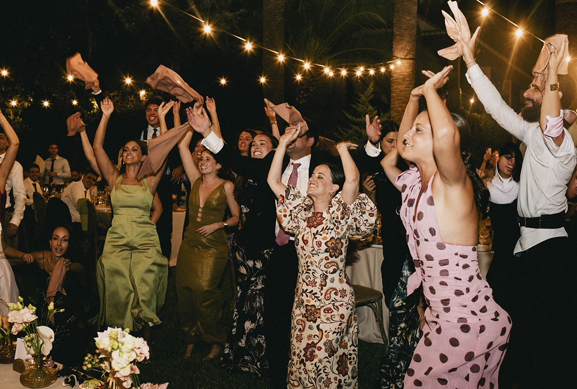 Wedding guests dancing and celebrating with raised arms during a lively party in Mallorca.