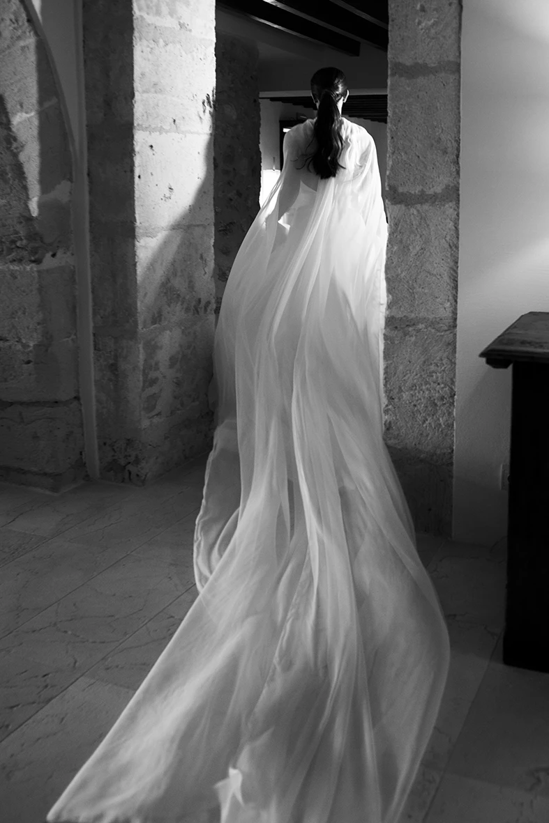Bride entering a room with a long veil in motion, black and white image – Wedding photographer in Mallorca – Inma del Valle -