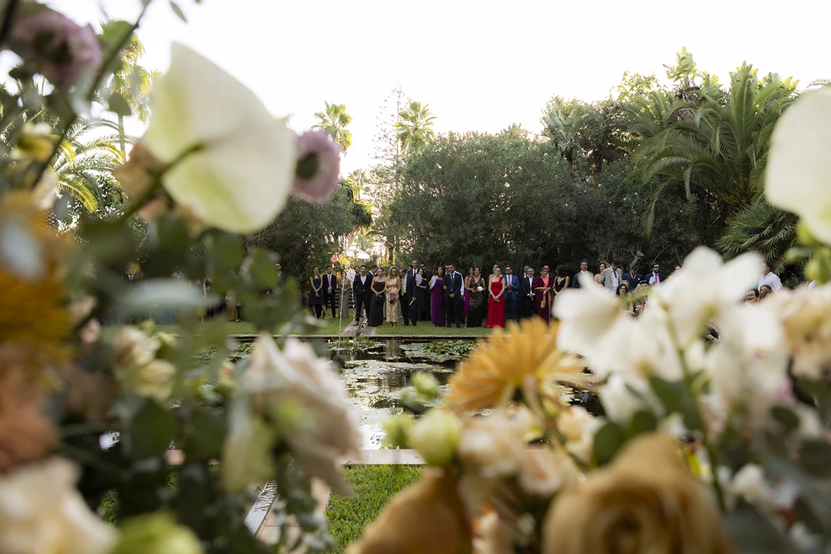Wedding guests seen through flowers at Finca Santa Cirga – Wedding photographer in Mallorca – Inma del Valle -