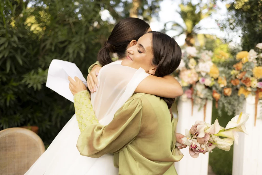 Bride hugging a guest holding flowers at Finca Santa Cirga – Wedding photographer in Mallorca – Inma del Valle -
