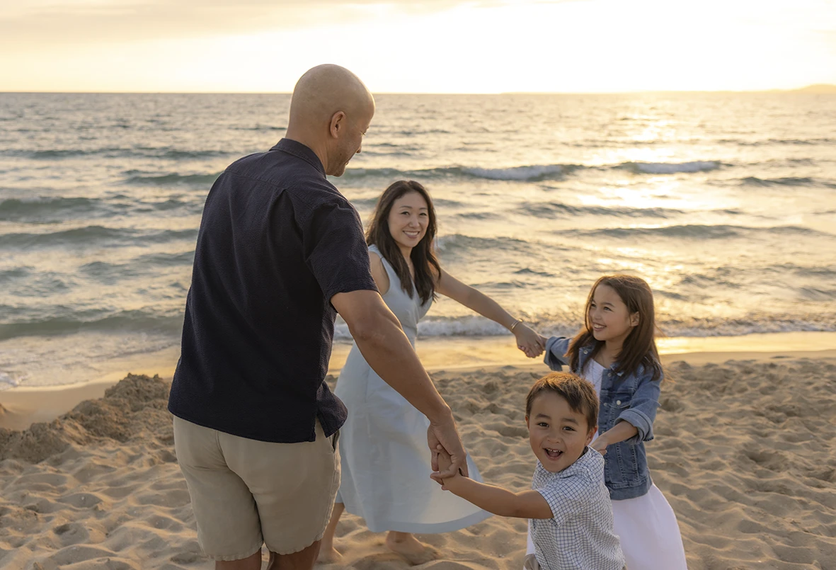 Family playing in a circle at sunset by the sea during a session with Inma del Valle in Mallorca.