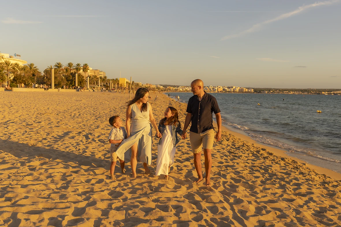 Family walking hand in hand along the beach at sunset in Mallorca with Inma del Valle.