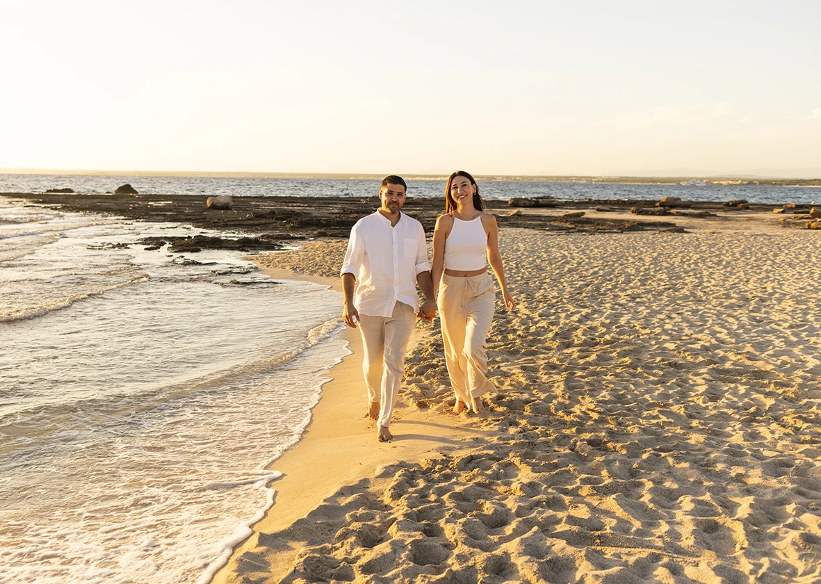Pareja caminando de la mano por la orilla del mar al atardecer durante una sesión de fotografía de familias en Mallorca