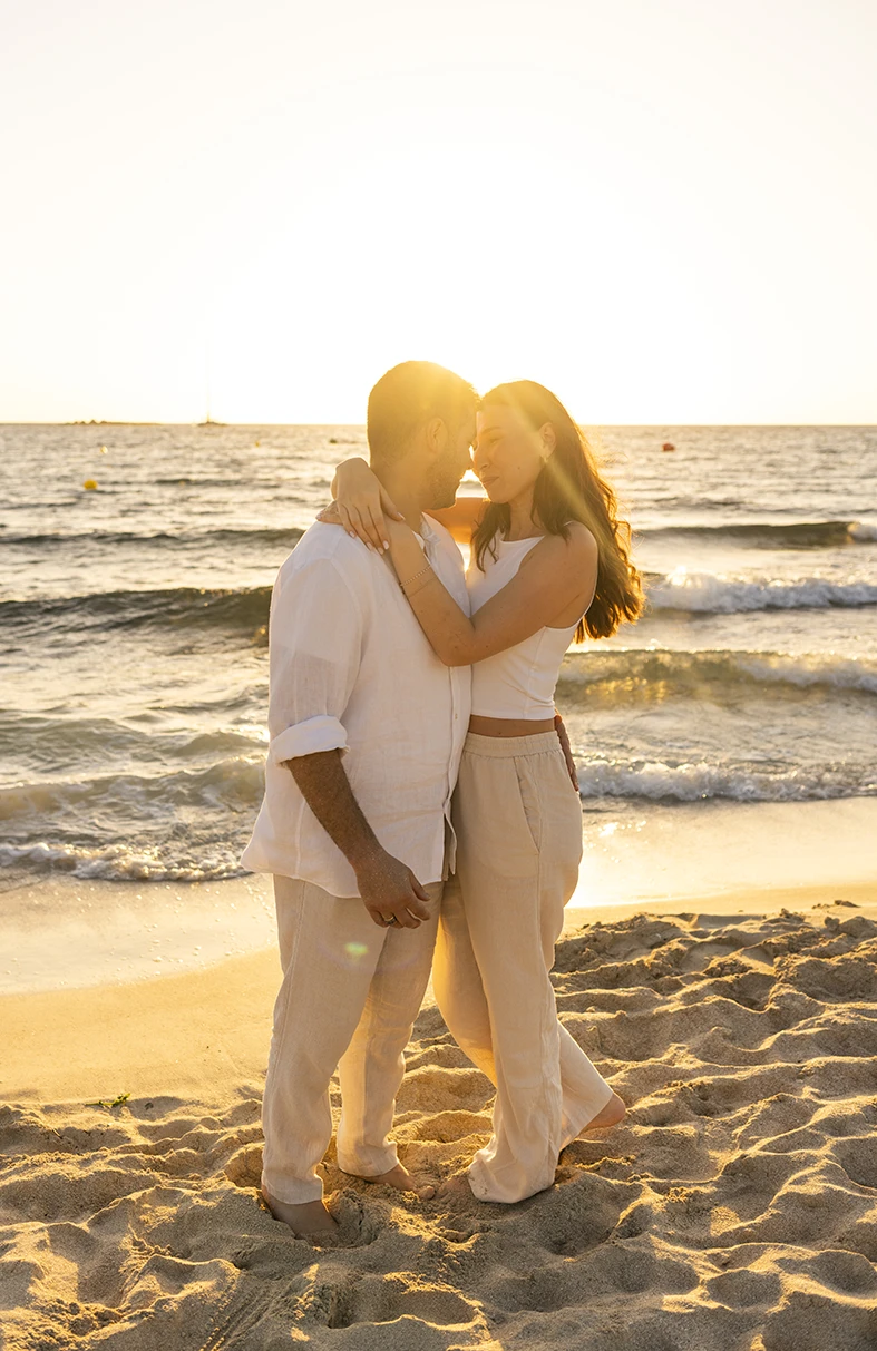 Pareja abrazándose con el mar al fondo y la luz dorada del atardecer durante una sesión de fotografía de familias en Mallorca